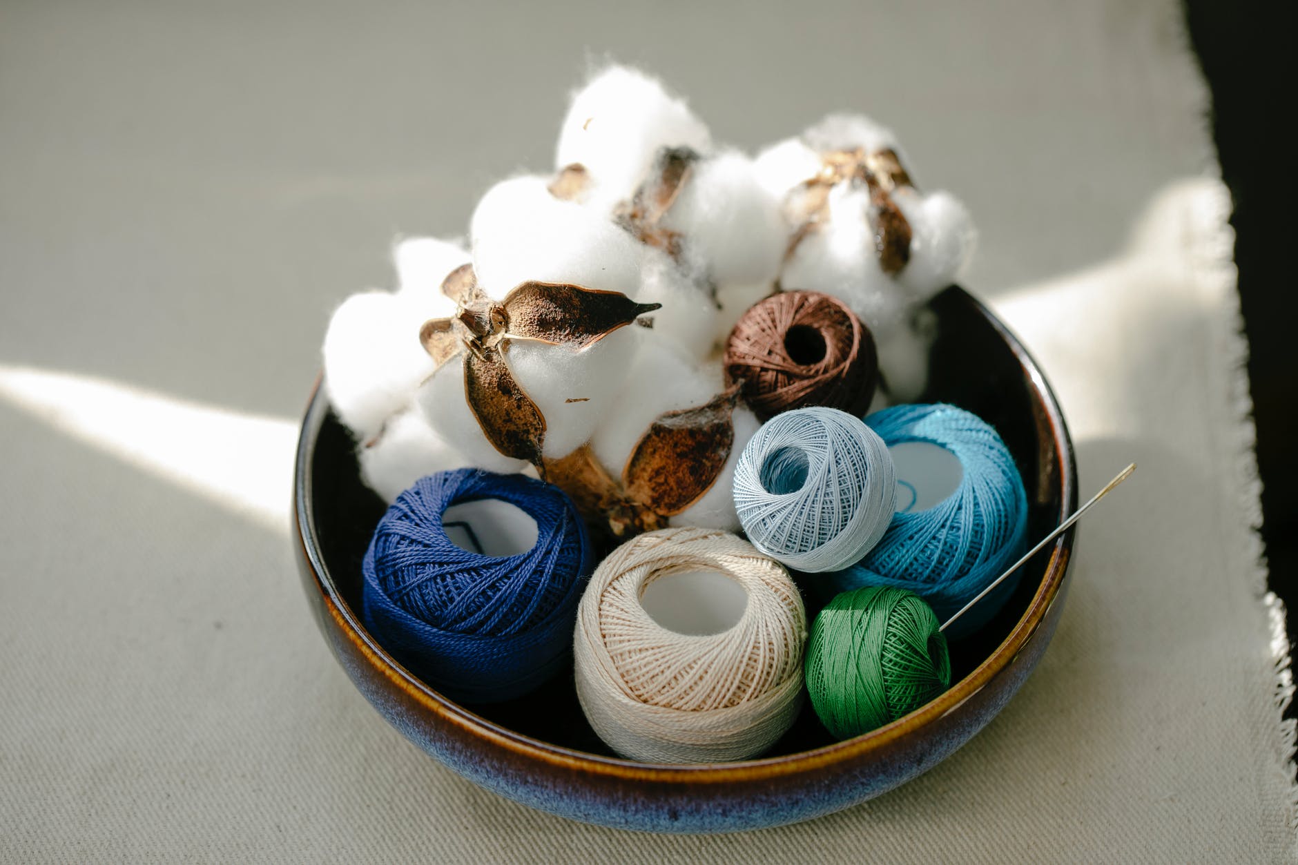 bowl with various threads and balls of cotton fiber